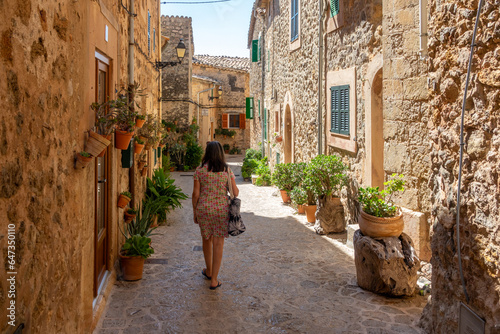 50 year old woman with gray hair walking through the narrow and ornate streets of Valldemossa (Mallorca, Spain) on a sunny summer morning photo