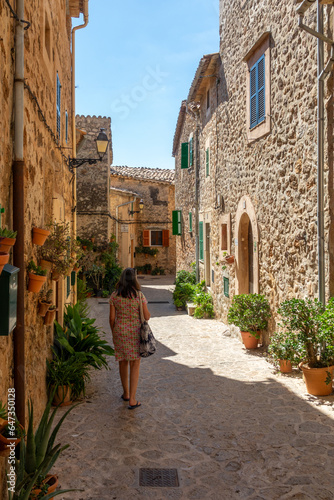 50 year old woman with gray hair walking through the narrow and ornate streets of Valldemossa (Mallorca, Spain) on a sunny summer morning © Miguel Ángel RM
