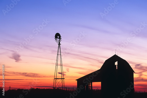 Beautiful sunset of a windmill and barn silhouetted in Indiana