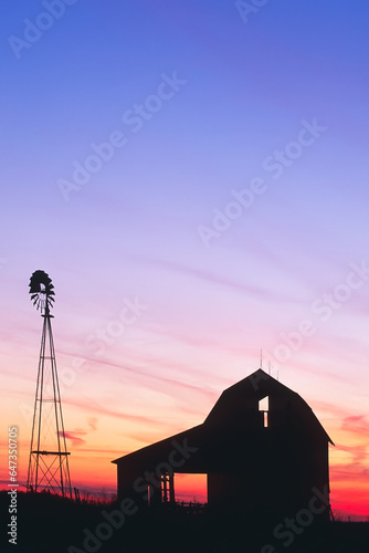 Beautiful sunset of a windmill and barn silhouetted in Indiana