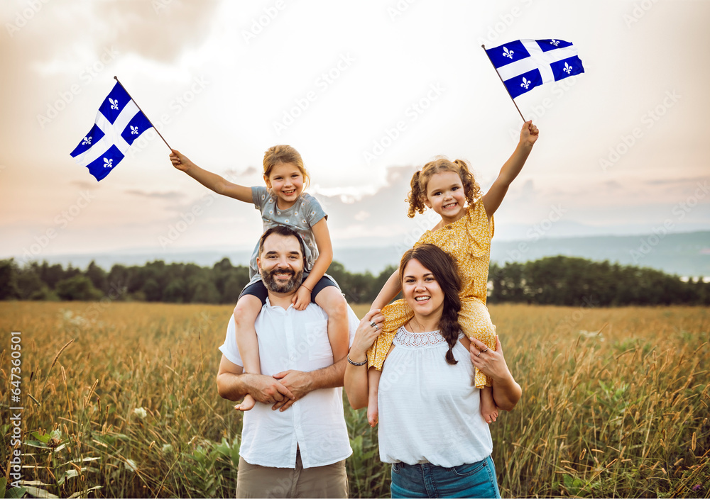 Fototapeta premium A Patriotic family waving Quebec flags on sunset