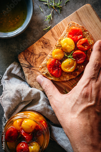 Obraz na płótnie mano cogiendo una tostada con tomates cherry confitados