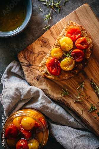 Canvastavla tostada con tomates cherry confitados en una tabla de cortar de madera