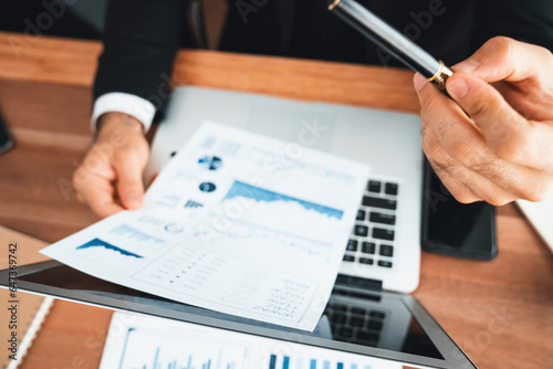 Diverse group of business analyst team analyzing financial data report paper on office table. Chart and graph dashboard by business intelligence analysis for strategic marketing planning Habiliment