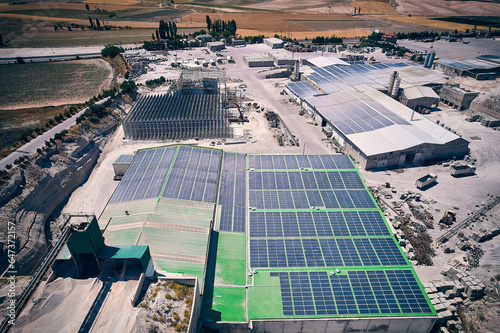 Aerial view of industrial buildings with photovoltaic panels installed on roof. Solar panels on industrial building roof. Solar PV panels aerial view