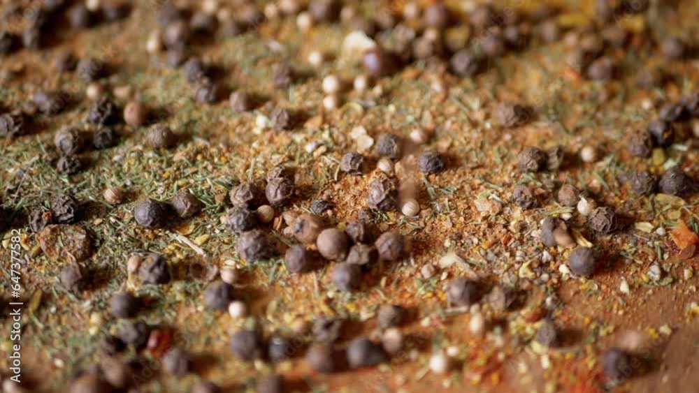 Dried Spices Falls on a Rotating Wooden Background of Colorful Spices. Close up. Slow motion. Scattered Indian spice mix, black peppercorns, turmeric, paprika, coriander, oregano. Background, texture. Dried Spices Falls on a Rotating Wooden Background of Colorful Spices. Close up. Slow motion. Scattered Indian spice mix, black peppercorns, turmeric, paprika, coriander, oregano. Background, texture.