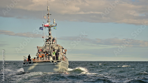 Okręt  wojenny płynący na morzu przed zachodem słońca photo