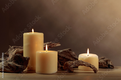 Burning candles and of old wooden snags on an old oak table.