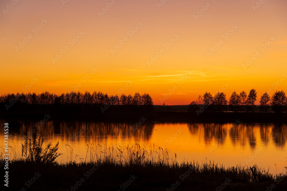 beautiful orange-yellow sunset on the lake in spring