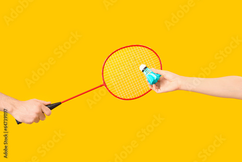 Hands holding badminton racket and shuttlecock on orange background © Pixel-Shot