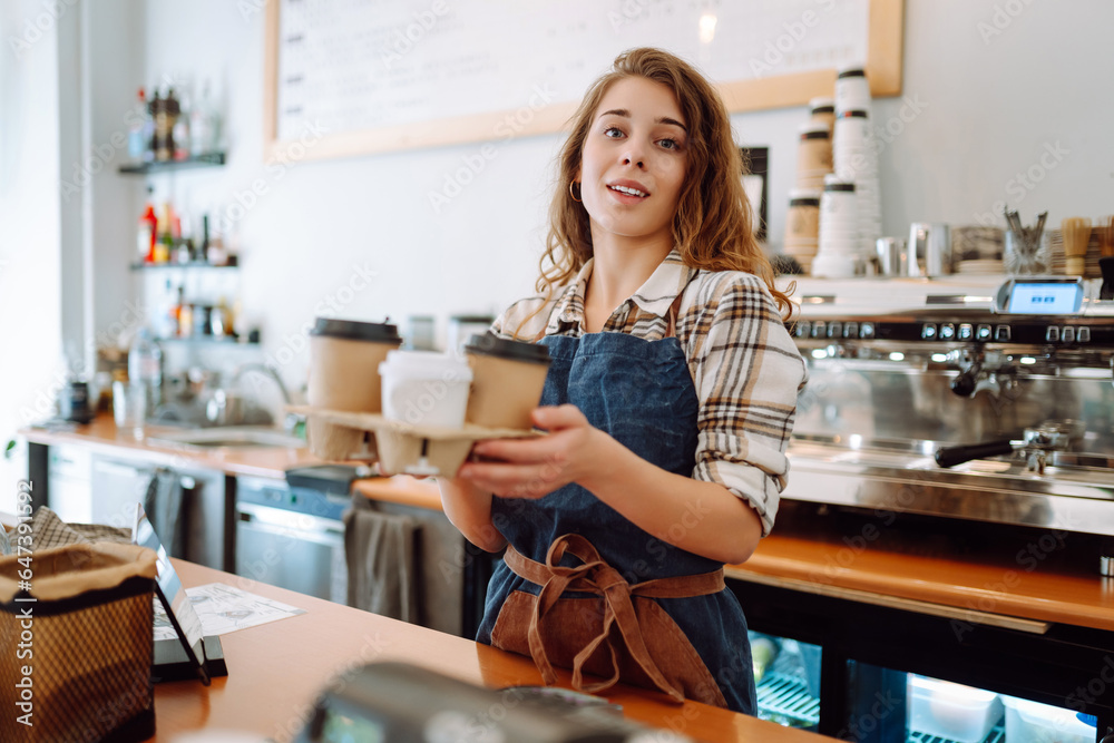 Portrait of a young female barista with a glass holder with drinks to go. Takeaway delivery concept. Portrait of a young female barista with a glass holder with drinks to go. Takeaway delivery concept.