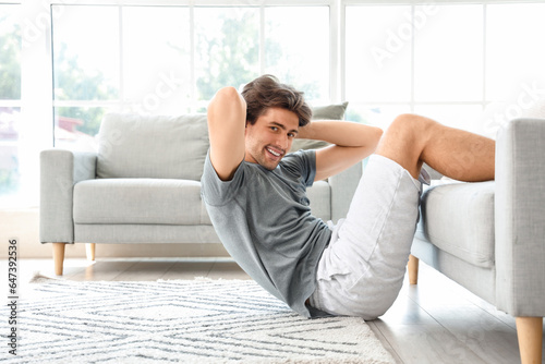 Handsome young man in sportswear swings press at home