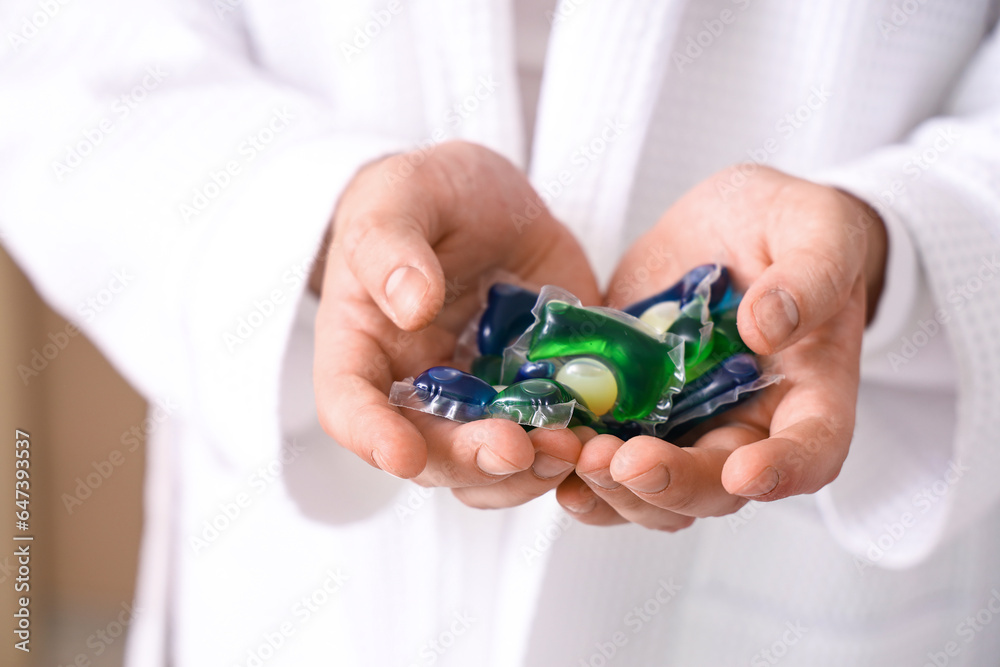 Young man with laundry capsules, closeup Young man with laundry capsules, closeup