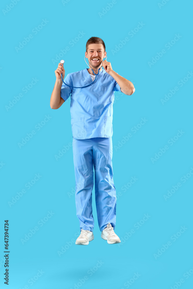 Jumping male doctor with stethoscope on blue background Jumping male doctor with stethoscope on blue background