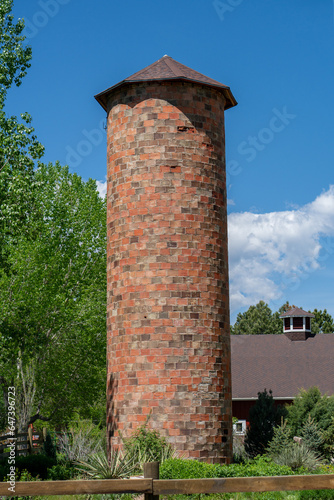 Old Brick Grain Silo With Cottonwood Trees Against Blue Sky