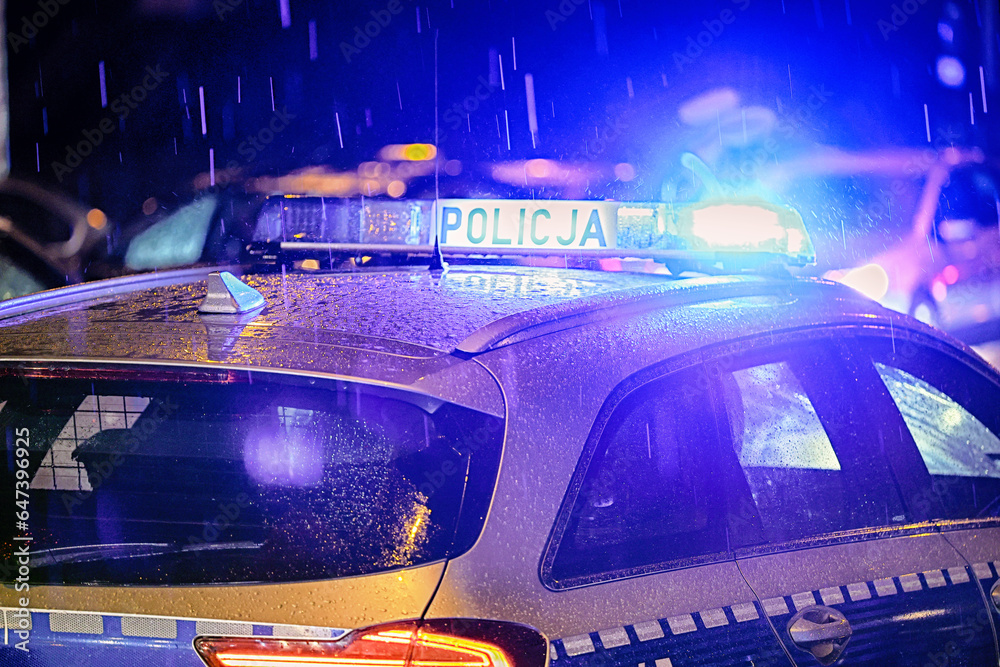 Policja polska radiowóz w akcji na ulicy w ruchu. Policja w deszczu.  - obrazy, fototapety, plakaty 