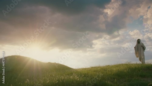 Christ as the Eternal Pilgrim descending slowly on a hill at sunset. photo