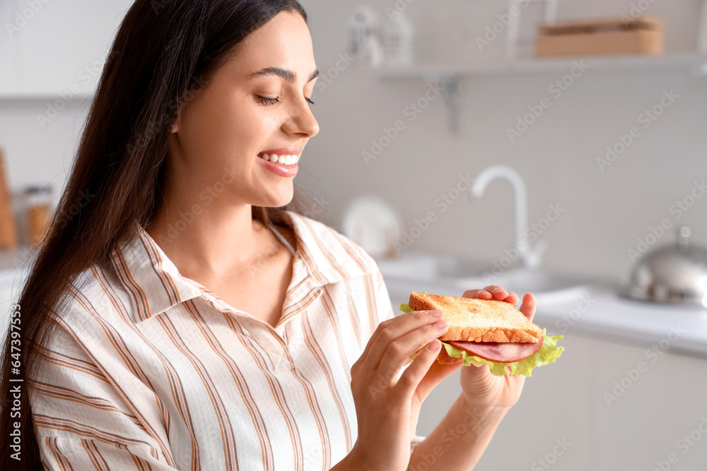 Young woman with tasty sandwich in kitchen, closeup Young woman with tasty sandwich in kitchen, closeup