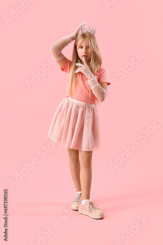 Cute little girl in tiara on pink background