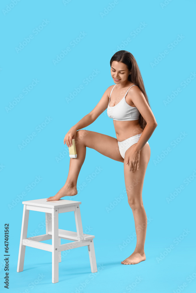 Beautiful young woman with liposoluble wax cartridge for epilation on blue background