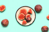 Plate with fresh juicy cut figs on turquoise background