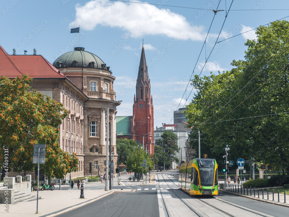 Summer cityscape of Poznań, Wielkopolska, Poland. In the photo: Modern tram at Fredry street, building of Adam Mickiewicz University in Poznan (WFPiK UAM), catholic church and Okrąglak building.