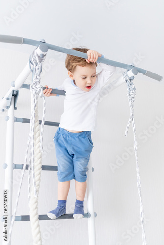 a child a boy does sports or exercises on the Swedish wall of the house