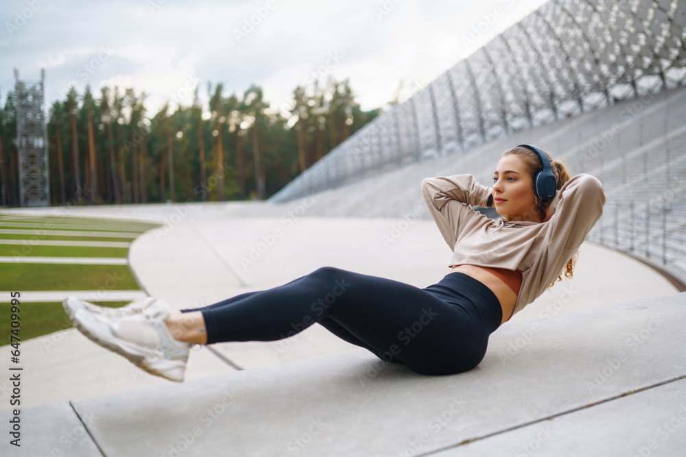 Sportswoman doing exercises on the street. A woman in sportswear goes in for sports, does exercises outdoors on a sunny day. Concept of sport, activity.