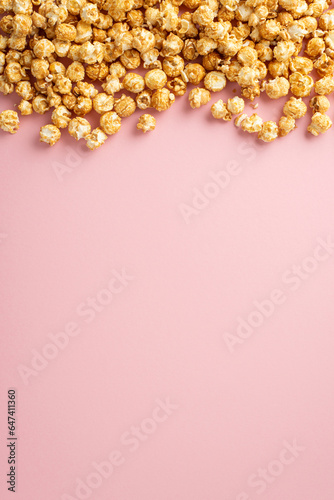 Film Buff's Dream: Vertical top view of mouthwatering popcorn on a pastel pink surface, space available for text or adverts