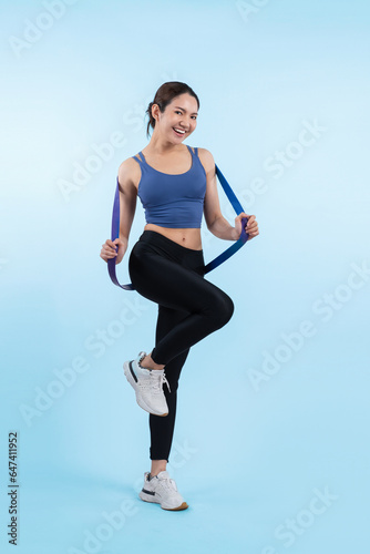 Vigorous energetic woman in sportswear portrait stretching resistance sport band. Young athletic asian woman strength and endurance training session workout routine concept on isolated background.