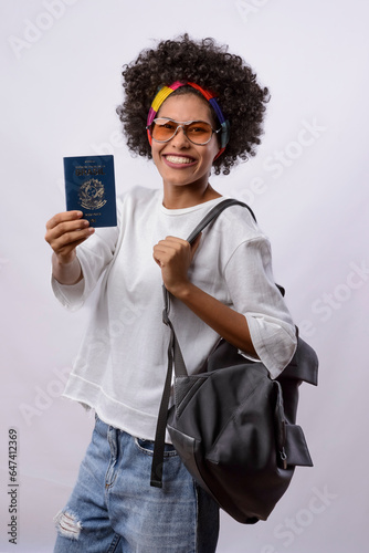 Brazilian passport. Young black woman with black power curly hair, white t-shirt, smiling and holding a Brazilian passport. photo
