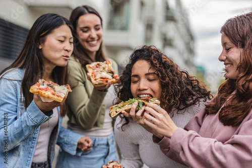 beautiful young fun women enjoying delicious pizza - tourist women in European city with takeaway food -
