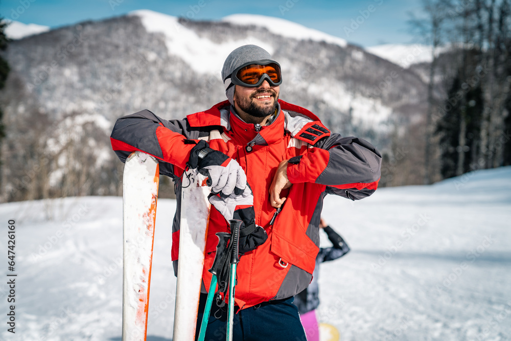 Smiling male skier enjoying the moment. Athletic happy man admiring the mountain range covered with snow during winter vacation.