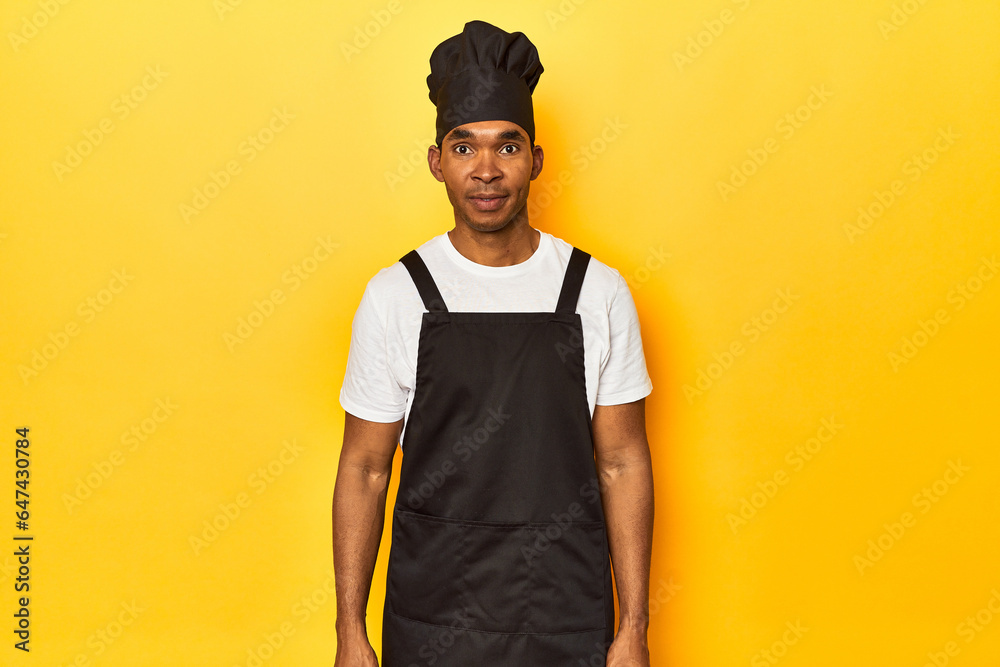 African American chef in professional attire, yellow studio backdrop. African American chef in professional attire, yellow studio backdrop.