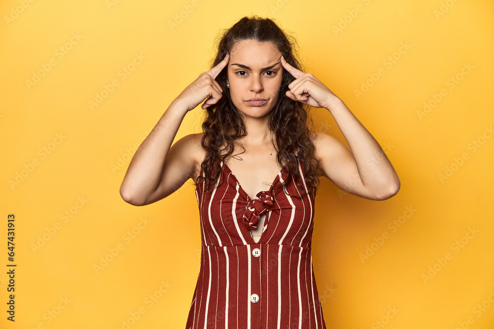 Young Caucasian woman, yellow studio background, focused on a task, keeping forefingers pointing head. Young Caucasian woman, yellow studio background, focused on a task, keeping forefingers pointing head.