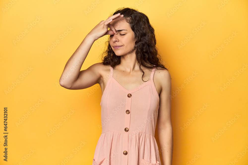 Obraz premium Young Caucasian woman, yellow studio background, having a head ache, touching front of the face.