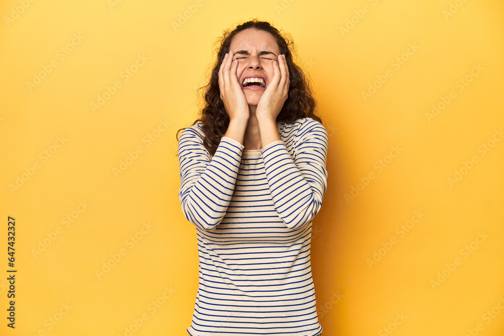 Young Caucasian woman, yellow studio background, whining and crying disconsolately. Young Caucasian woman, yellow studio background, whining and crying disconsolately.