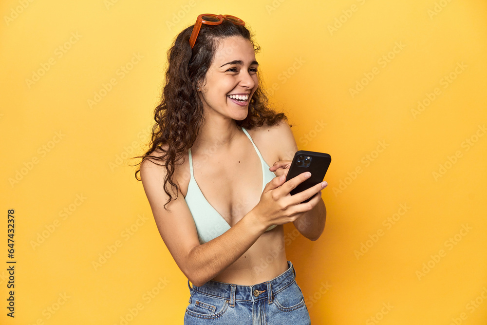 Woman laughing at phone content, vivacious yellow scene. Woman laughing at phone content, vivacious yellow scene.