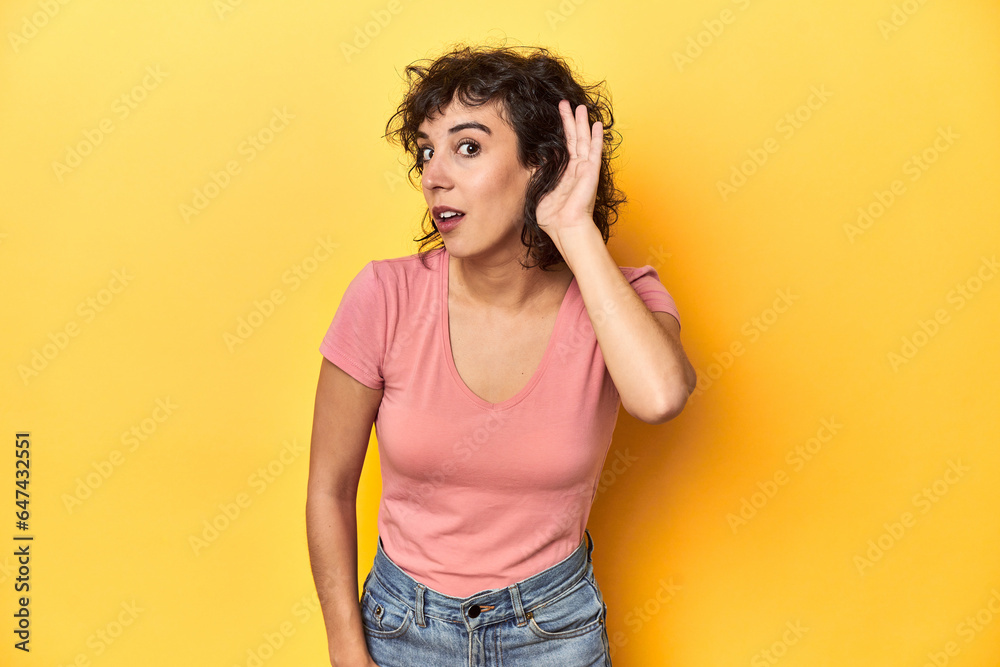 Curly-haired Caucasian woman in pink t-shirt trying to listening a gossip. Curly-haired Caucasian woman in pink t-shirt trying to listening a gossip.
