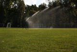 Lawn watering system for playing football. Spraying water on a grassy field for playing a sports game