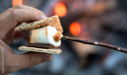 Foto Closeup of person roasting marshmallow enjoying s'more by a campfire