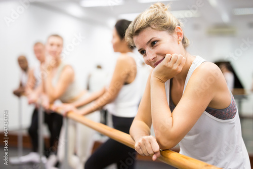 Fototapeta Naklejka Na Ścianę i Meble -  Group of people doing exercises using barre in gym with focus to fit athletic toned ..woman in foreground in health and fitness concept
