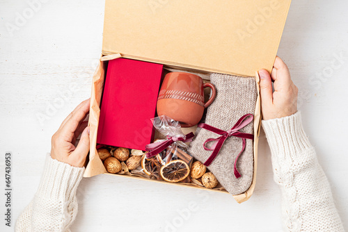 Preparing care package with warm socks, book, coffee cup, aroma spices. Personalized eco friendly basket for fall, winter holidays, christmas, wishig recovery to family, friend. Get well soon gift box