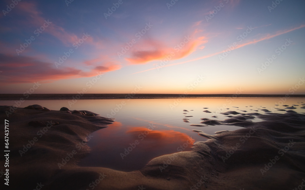 Wolken spiegeln sich kurz nach Sonnenuntergang im Wasser