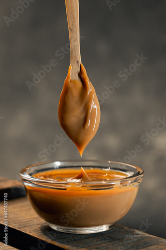 closeup of a glass saucepan or bowls with delicious Argentine dulce de leche on wood