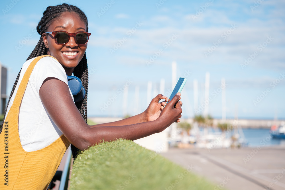 Young woman with smartphone enjoying an afternoon on the promenade. Concept: lifestyle, sunset, outdoors.