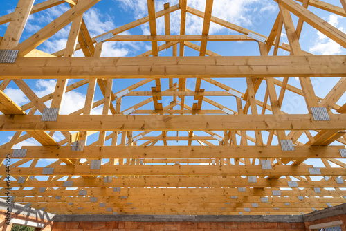 Frame of new house with wooden roof without coating against blue sky on background