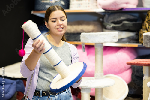 Young female customer picking out cat scratcher in pet store photo