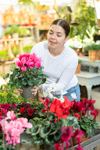 Woman looking to buy potted cyclamen in container garden shop