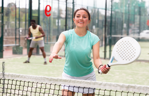 Portrait of cheerful woman paddle tennis player during friendly doubles couple match with male friend at court © JackF